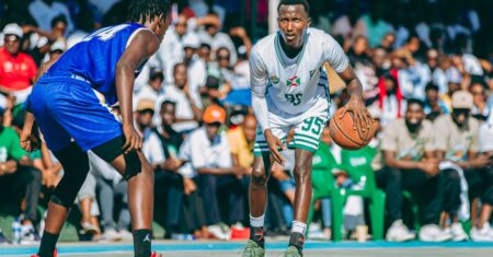 Estratégias para apostas em basquete Um jogador em camisa branca dribla a bola em uma quadra de basquete cheia de torcedores.