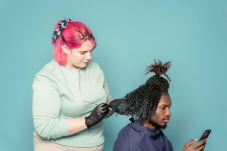 27 negócios de beleza abrem por hora e a captação de clientes para salão de beleza fica sem dono Cabeleireira de luvas aplica coloração no cabelo de um cliente que segura o celular durante o atendimento