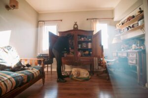 Pessoa organizando as prateleiras de um armário de madeira na sala de uma casa habitada